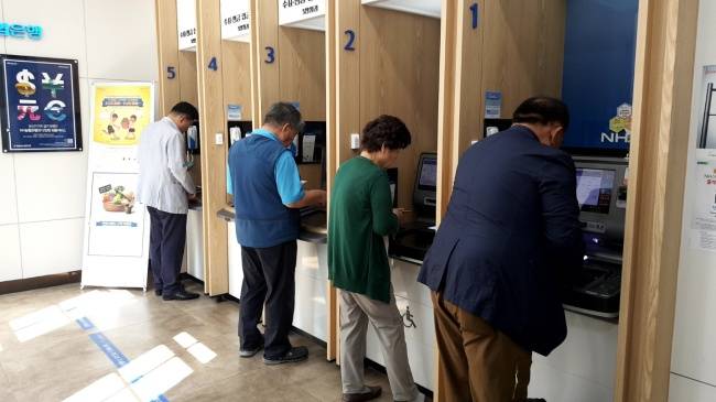 [사진=서울 종로구의 한 은행 현금자동입출금기(ATM)에서 금융업무를 보고 있는 노인들]