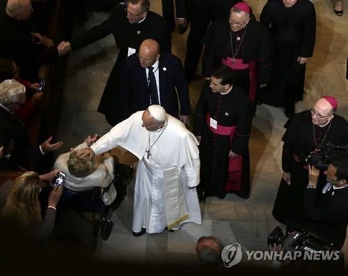 교황이 27일(현지시간) 미국 필라델피아 성 마르틴 성당에서 휠체어에 앉은 한 여성의 머리를 만지고 있다.