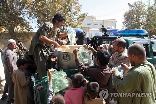 4일 아프간 쿤두즈에서 주민들이 아프간 치안당국의 음식 배급을 받고 있다.(EPA=연합뉴스)