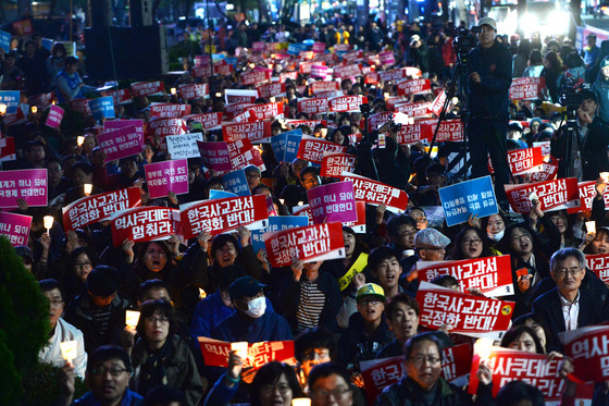 24일 오후 중구 서울 파이낸스 빌딩 앞에서 열린 역사교과서 국정화 저지를 위한 제2차 범국민 촛불문화제에서 참가자들이 촛불을 들고 구호를 외치고 있다. /뉴스1