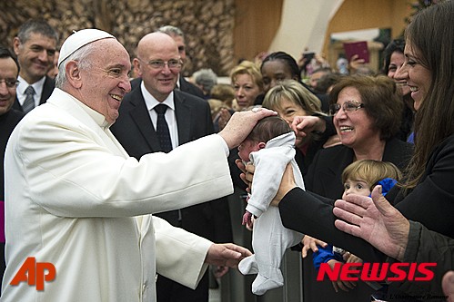 【바티칸=AP/뉴시스】프란치스코 교황이 21일(현지시간) 바티칸에서 직원들을 위한 연례 크리스마스 축하 행사에 참석해 한 여성 직원이 내민 아기의 머리를 쓰다듬고 있다. 2015.12.22