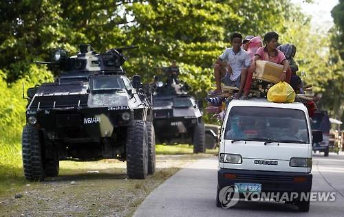 24일 이슬람 반군이 기독교 마을을 공격한 필리핀 남부 지역에서 주민들이 장갑차를 지나고 있다. (AFP=연합뉴스)