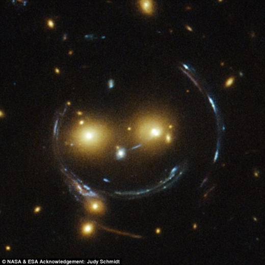 두 눈처럼 보이는 것은 은하들이며, 웃는 것처럼 보이는 선은 사실 강력한 중력 렌즈 효과로 빛이 굴절돼 보이는 것이다.