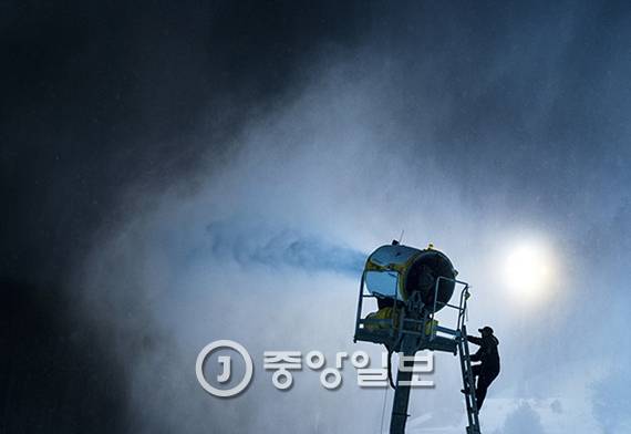 스키장 슬로프 관리직원이 고정형 제설기를 가동시키고 있다. 이 제설기는 자동으로 방향을 바꿔가며 눈을 뿌린다.