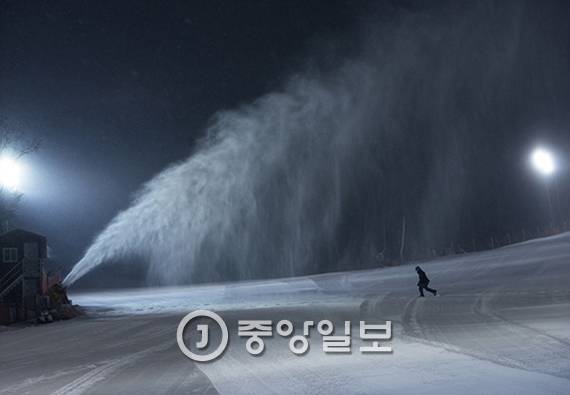 슬로프 관리직원이 제설기에서 뿜어져 나오는 눈의 상태를 살피고 있다.