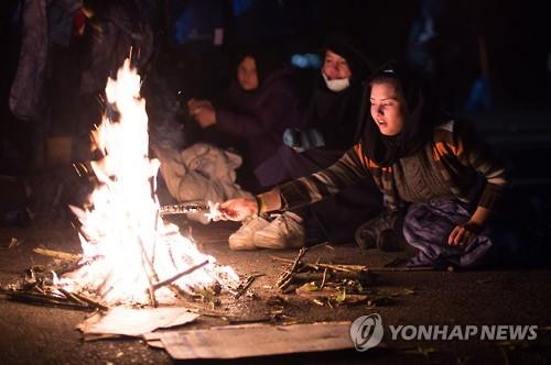 2015년 10월28일(현지시간) 독일 파사우 근처에서 난민 여성들이 수용시설로 실어다 줄 버스를 기다리며 모닥불을 피우고 있는 모습(AP=연합뉴스 자료사진)