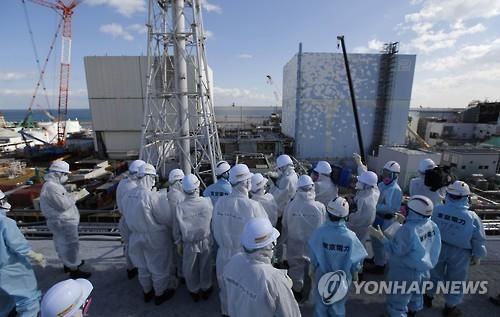 지난 10일 후쿠시마 제1원전 원자로 건물들이 보이는 곳에서 도쿄전력 관계자들로부터 설명을 듣고 있는 취재진(후쿠시마 제1원전=공동취재단)
