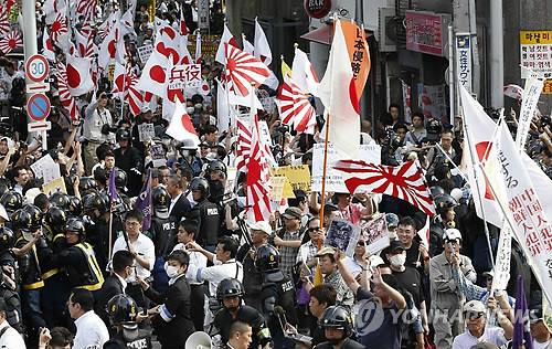2013년 7월 18일 일본 도쿄도(東京都) 신주쿠(新宿)구에서 재일 한국·조선인을 배격하는 주장을 담은 시위대(오른쪽)가 행진하고 있고 이에 반대하는 시민들(왼쪽)이 항의하는 모습.(도쿄 교도=연합뉴스 자료사진)