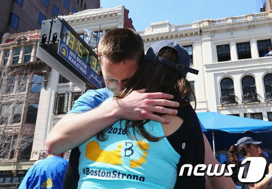 패트릭 다운즈가 보스턴 마라톤대회 결승선을 통과한 후 아내를 끌어안고 있다. © AFP=뉴스1