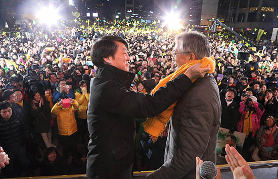 ⓒ사진공동취재단 : 2012년 12월15일 서울 광화문 유세에서 예정에 없이 깜짝 등장한 안철수 전 후보가 자신이 매고 있던 노란 목도리를 문재인 당시 민주통합당 후보에게 둘러주고 있다.