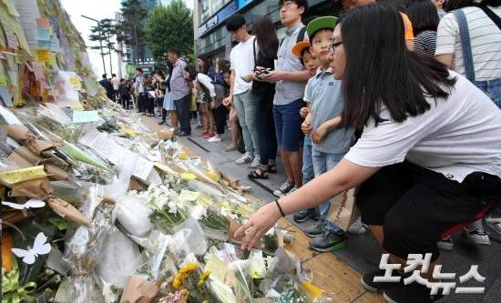 21일 오후 '강남 묻지마 살인' 추모현장인 강남역 10번 출구를 찾은 시민들이 추모의 글을 적은 메모지를 붙이고 헌화를 하고 있다. (사진=황진환 기자)