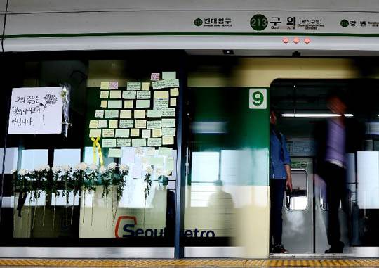 A Screen Door, Now a Door of Memories: On May 31, notes and chrysanthemums are posted next to the screen door 9-4 in the platform at Guui Station, line 2 of the Seoul Metro. Citizens continue to visit this site, where a nineteen-year-old temporary worker died on duty. Kim Chang-gil