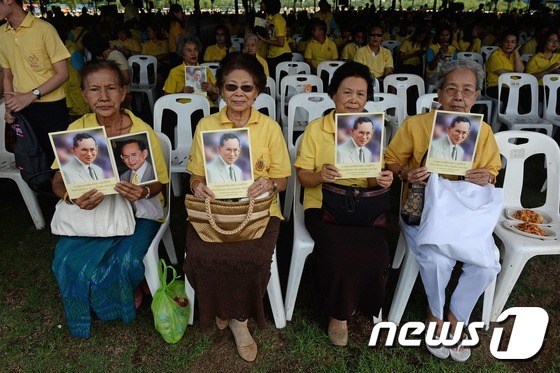 9일(현지시간) 방콕에서 여성들이 즉위 70주년을 맞은 푸미폰 아둔야뎃(88) 국왕의 사진을 들고 있다. © AFP=뉴스1