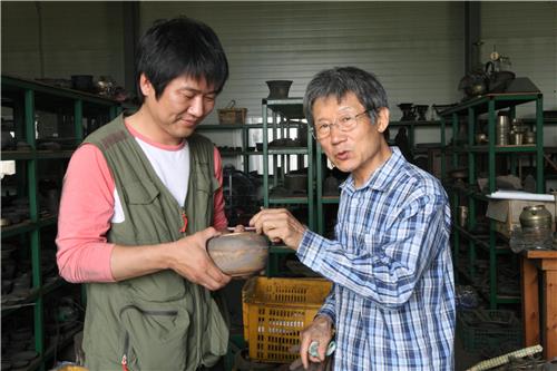 국가지정중요무형문화재 77호 김수영(사진 오른쪽)씨가 장남 범진(43)씨에게 유기제작 과정에 대해 설명해 주고 있다