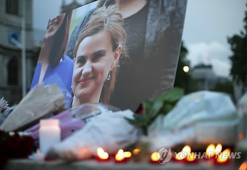 16일(현지시간) 영국 런던 의사당 광장의 임시 추모단에서 이날 총격 테러로 사망한, 노동당 소속 조 콕스(41) 하원의원의 사진이 촛불과 함께 빛나고 있다.［AFP=연합뉴스］