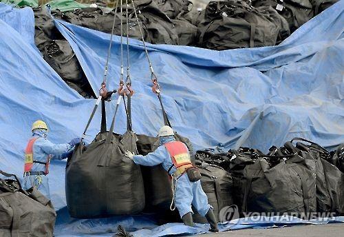 일본 후쿠시마현의 오염물 임시 보관장에서 작업원들이 오염 제거작업으로 수거된 흙이 든 대형 자루를 장비를 이용해 옮기고 있다. [교도=연합뉴스 자료사진]