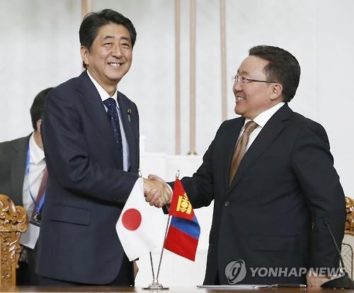 (울란바토르 교도/AP=연합뉴스) 아베 신조(왼쪽) 일본 총리와 차히야 엘벡도르지 몽골 대통령이 14일 몽골의 울란바토르에서 기자회견을 마치며 악수를 하고 있다.