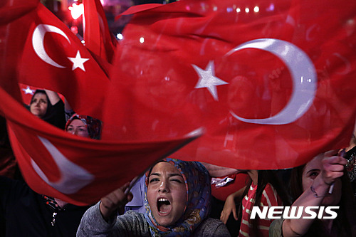 【이스탄불=AP/뉴시스】한 여성이 25일 이스탄불의 탁심 광장에서 열린 쿠데타 반대 집회에서 대형 터키 국기를 흔들며 구호를 외치고 있다. 터키 정부는 이날 보스포러스 대교의 이름을 '7·15 순교자의 다리'로 개명하기로 결정했다면서 이는 쿠데타에 저항하다 희생된 민간인들을 기리기 위해서라고 말했다. 2016.7.26