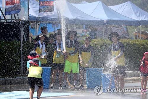 폭염의 날씨를 보인 지난 12일 강원 춘천시 송암스포츠타운에서 개막한 춘천국제레저대회 행사장에서 자원봉사자들이 어린이 관람객에게 물을 뿌려주고 있다.