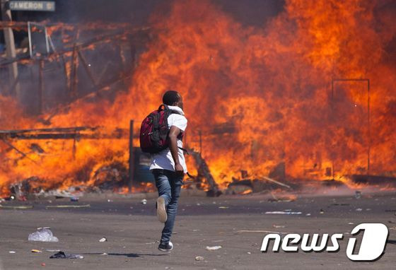 짐바브웨 반정부 시위 현장에서 26일(현지시간) 한 청년이 불에 타고 있는 바리케이드 앞으로 뛰어가고 있다. © AFP=뉴스1