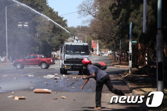 짐바브웨 경찰이 26일(현지시간) 짐바브웨 수도 하라레에서 반정부 시위대를 향해 물대포를 쏘고 있다. © AFP=뉴스1