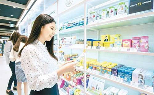 한 고객이 올리브영 매장에서 제품을 살펴보며 쇼핑을 하고 있다.