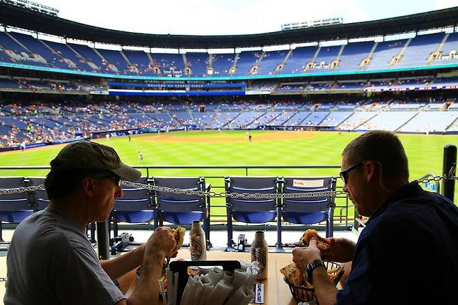 맥주와 음식을 즐기며 야구 경기를 관람하는 사람들.
