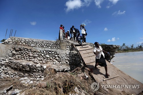 7일(현지시간) 아이티 샹탈 지역에서 주민들이 허리케인 매슈에 무너져 내린 다리를 지나고 있다. [EPA=연합뉴스]