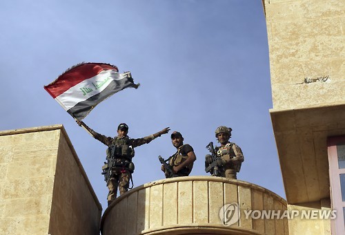21일 이라크 대테러부대 대원들이 이라크 제2도시 모술 외곽의 바르텔라를 수니파 무장조직 '이슬람국가'(IS)로부터 탈환한 후 국기를 흔들고 있다. [AP=연합뉴스]