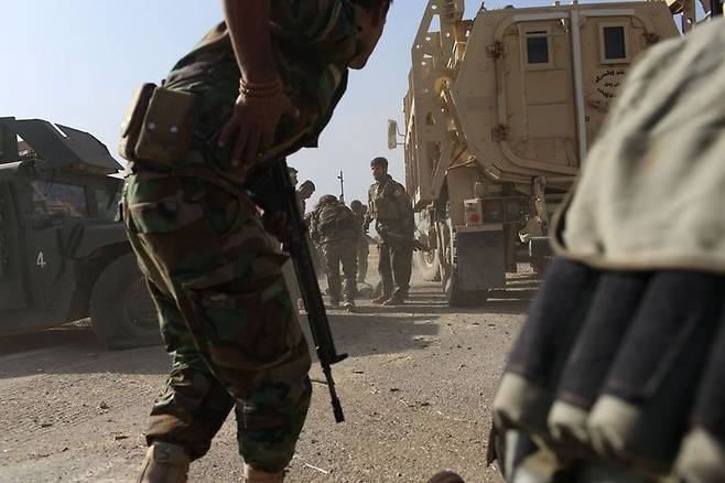 20일 이라크 모술 인근의 바시카에서 이슬람국가(IS)의 매복 공격을 받은 쿠르드민병대(PAK)대원들이 쓰러진 동료를 트럭 옆으로 옮겨 은신하고 있다.