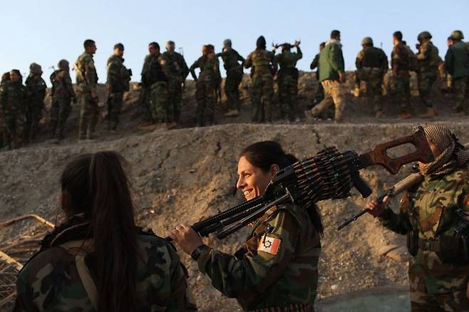 20일 이라크 모술 인근의 바시카에서 이슬람국가(IS)와의 전투를 앞둔 쿠르드민병대(PAK) 소속 여군들이 어깨에 총을 메고 밝게 웃으며 얘기를 나누고 있다.