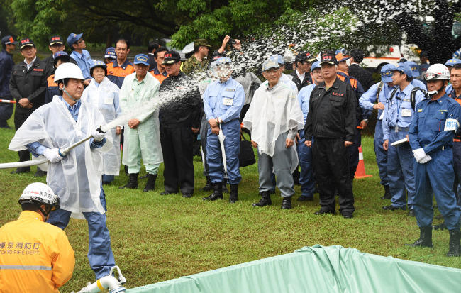 지난해 9월 1일 ‘방재의 날’ 소방훈련에 참가한 아베 신조 총리가 도쿄(東京)도 다치카와(立川)시에서 호스로 물을 뿌리고 있다. [사진제공·아사히신문]