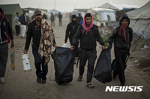 【칼레=AP/뉴시스】프랑스 칼레 난민촌에서 25일(현지시간) 난민들이 정부의 명령에 따라 다른 시설로 옮기기 위해 소지품들을 챙겨 걸어가고 있다. 2016.10.25