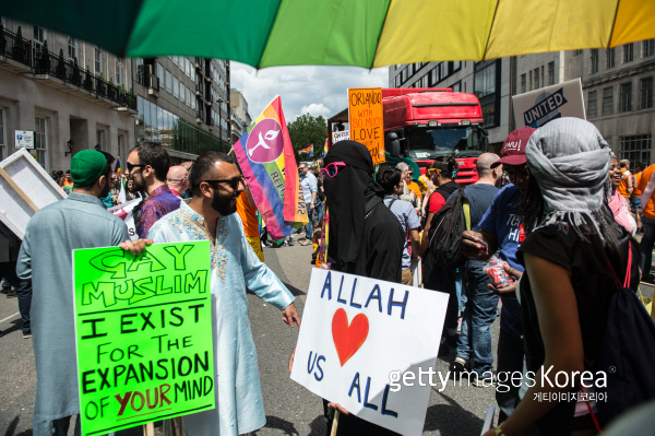 영국 런던에서 6월25일 열린 LGBT 가두 행진 축제 동안 무슬림 동성애자들이 “알라는 우리 모두를 사랑한다” “나는 여러분의 생각의 폭을 넓히려고 여기 있다”는 팻말을 들고 대화를 나누고 있다. Photo by Chris J Ratcliffe/Getty Images
