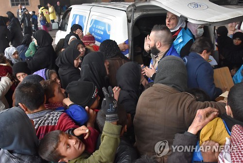 1일(현지시간) 알레포를 탈출한 난민들이 구호물자 차량 앞에서 물품을 받기 위해 몰려 있다. [AFP=연합뉴스]