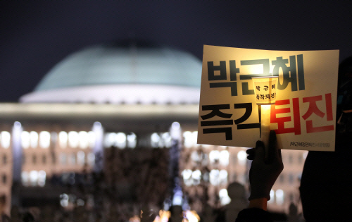 7일 오후 서울 여의도 국회의사당 앞에서 진행된 촛불집회에 참가한 한 시민이 박근혜 대통령 탄핵을 촉구하는 촛불을 들고 있다./연합뉴스