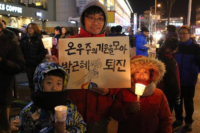 10일 춘천에서 열린 촛불집회에 아이들과 참여한 이종음(41)씨가 `온 우주의 기운을 모아 박근혜 퇴진'이라고 적힌 손팻말을 들고 있다.