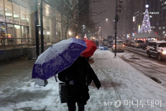 20일 기상청에 따르면 이날 전국은 찬 대륙고기압의 영향으로 새벽부터 눈이 오다가 낮에 대부분 그칠 것으로 보인다. 사진은 우산을 쓴 시민이 눈길을 지나는 모습. / 사진=머니투데이DB
