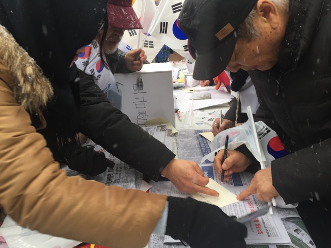 21일 박근혜 대통령 탄핵 반대 집회에 참가한 사람들이 ‘대통령께 러브레터 보내기’ 부스에서 편지를 쓰고 있다. 이현정 기자/rene@heraldcorp.com