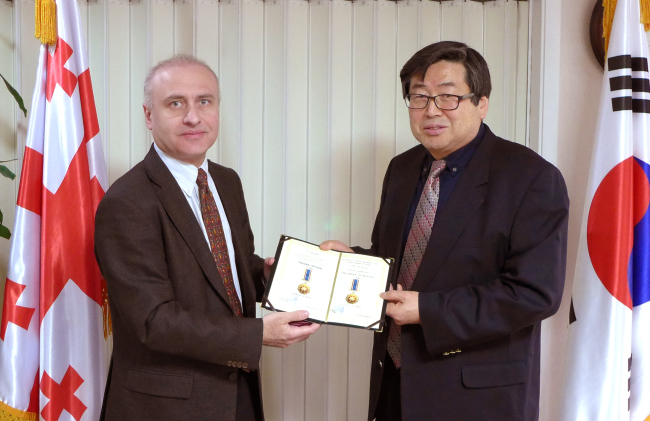 Georgian Ambassador Nikoloz Apkhazava (left) honors Cho Ju-kwan, professor of Russian language and literature at Yonsei University, who translated “The Knight in the Tiger’s Skin” into Korean, at a ceremony at the embassy in Seoul on Thursday. (Joel Lee/The Korea Herald)