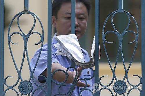 사진은 17일 쿠알라룸푸르의 북한 대사관에서 한 직원이 정문에 꽂힌 신문을 집는 모습. [EPA=연합뉴스자료사진]
