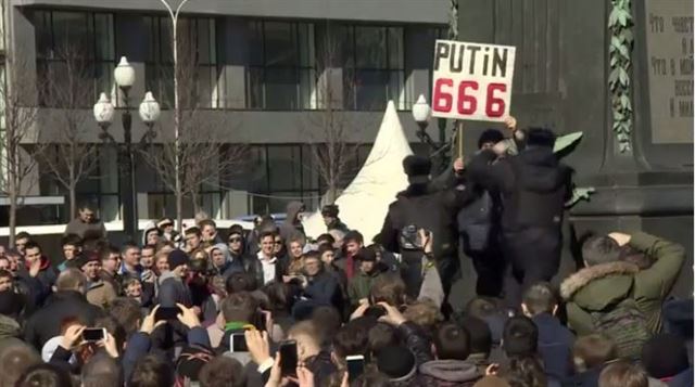 26일 러시아 모스크바 푸시킨 광장에서 '푸틴 666'이라고 적힌 손팻말을 들고 시위하던 남성이 경찰에 연행되고 있다. 영국 BBC캡처
