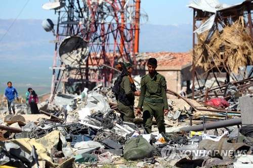 이달 25일(현지시간) 쿠르드 민병대 '인민수비대'(YPG) 대원이 시리아 북동부 데리크에서 터키군의 공습으로 파괴된 통신 시설의 잔해를 수색하고 있다. [AFP=연합뉴스]