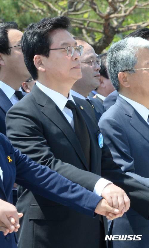 【광주=뉴시스】전진환 기자 = 18일 오전 제37주년 5·18 민주화운동 기념식이 열린 광주광역시 북구 운정동 국립 5·18민주묘지에서 참석자들이 임을 위한 행진곡 제창 중 정우택(왼쪽 두번째) 자유한국당 대표 권한대행 원내대표가 입을 다문 채 손을 흔들고 있다. 2017.05.18. amin2@newsis.com