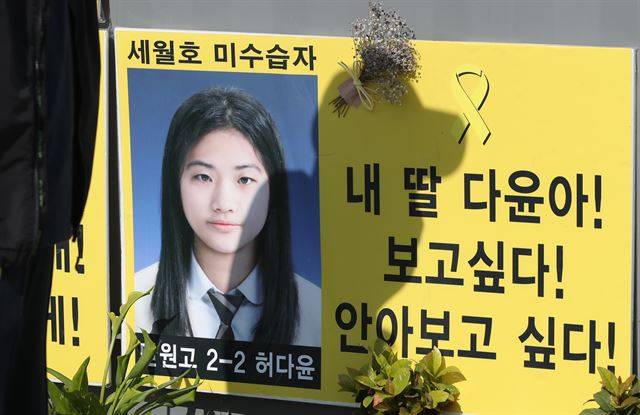 그림 1세월호 참사 미수습자인 단원고 학생 허다윤 양의 신원이 확인된 19일 오후 전남 목포신항 ‘미수습자 가족 만남의 장소’ 앞에 게시된 허 양 사진 위로 아버지 허흥환 씨의 그림자가 드리워져 있다.연합뉴스