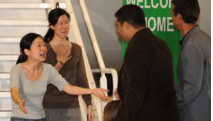 두만강변에서 취재하던 중 국경침범을 했다는 이유로 북한에 5개월 동안 억류됐던 미국인 여기자 유나 리(왼쪽)와 로라 링이 2009년 8월 방북한 빌 클린턴 전 미국 대통령과 함께 귀국한 뒤 가족과 상봉하고 있다.     CNN 홈페이지 캡처