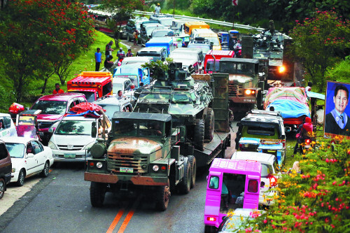 계엄령이 선포된 필리핀 남부 민다나오섬의 마라위시에서 25일 길게 늘어선 피난 차량들 사이로 정부군 장갑차를 실은 트럭이 이동하고 있다. 필리핀군은 현지에서 반란을 일으킨 무장단체를 진압하기 위해 헬기와 장갑차, 특수부대 등을 투입해 소탕작전을 벌이고 있다.   AP뉴시스