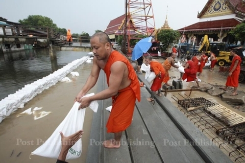 방콕지역에 내린 폭우로 수로의 물이 불어나자 한 사원의 승려들이 모래주머니로 방수벽을 세우고 있다[사진출처 방콕포스트]