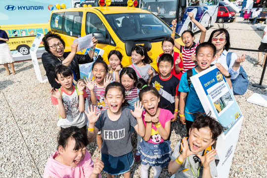 지난 28일 경기도 고양시 현대자동차 메가페어 전시장에서 어린이들과 복지기관 관계자들이 현대차가 제공한 통학버스와 함께 기념촬영을 하고 있다.    현대차 제공