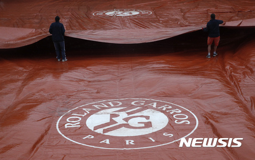 Stadium employees pull a protective canvas on a court as play has been suspended on all courts at the French Open because of rain, at the Roland Garros stadium, Saturday, June 3, 2017 in Paris. (AP Photo/Christophe Ena)256